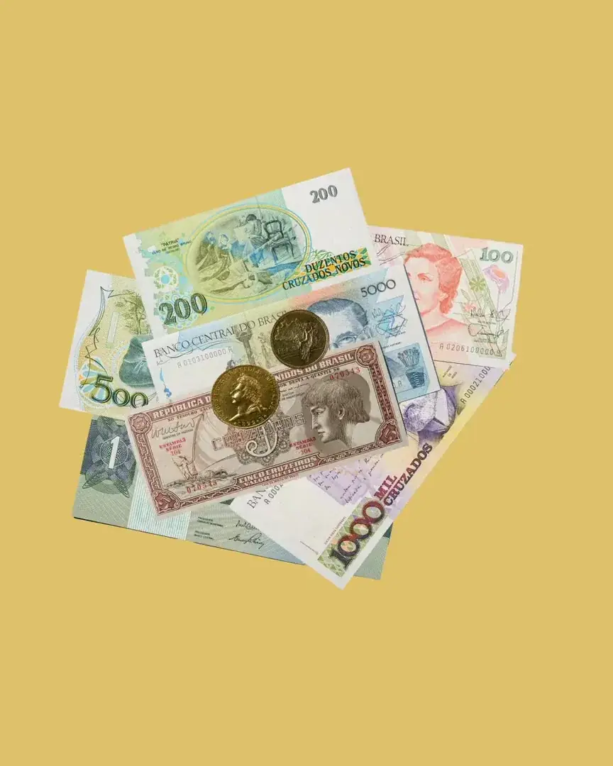 Cédulas e moedas caindo sobre fundo amarelo
