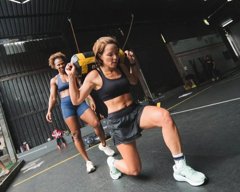 Atleta com sandbag em avanço no box da Crown