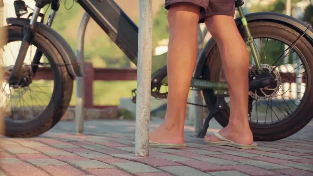Pés na areia e bicicleta ao pôr do sol